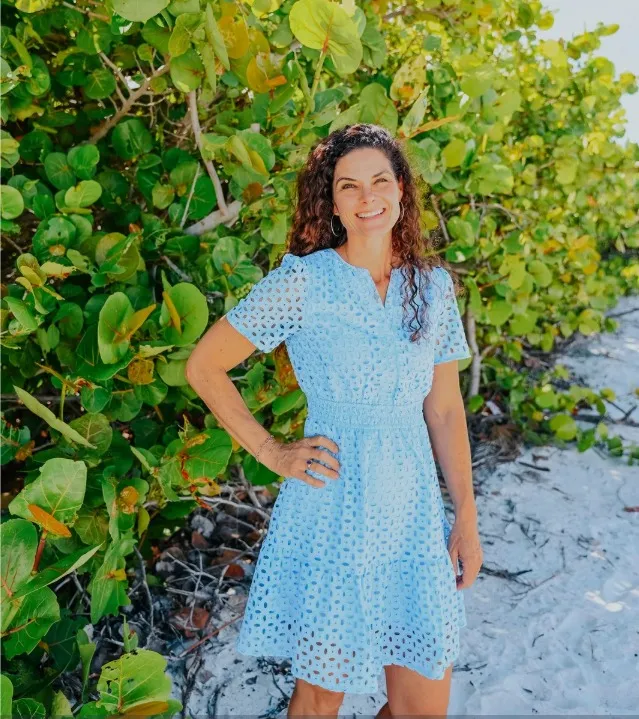 Tracy Lightburne smiling outdoors among sea grape leaves